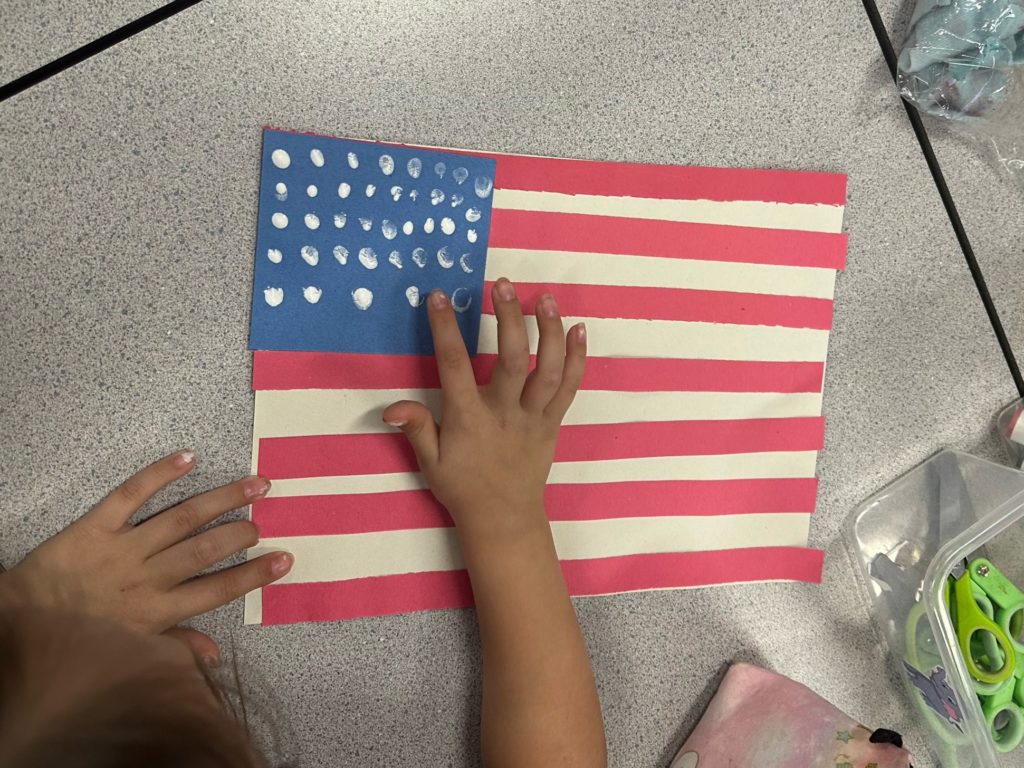 This is a photo of a child creating a paper U.S. flag.